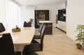 Dining table with set of chairs near the large window in kitchen. Interior photography. Open space living room with kitchen