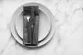 Dining table setting. Two grey plates with silver cutlery on the linen napkin. Minimalism style Royalty Free Stock Photo