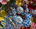 Dining tableware with colorful decorated plates and flowers on the table