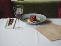 A dinner composition on a white tablecloth. A plate with meat dish, a dinner service and a glass of wine on a black Royalty Free Stock Photo