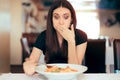 Woman Feeling Sick While Eating Bad Food in a Restaurant Royalty Free Stock Photo