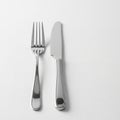 Dinner fork and knife are neatly placed side by side on a white Royalty Free Stock Photo