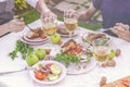 Dinner in the garden. People eat at the table with wine, grilled fish, fresh vegetables and herbs. Horizontal shot