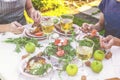 Dinner in the garden. People eat at the table with wine, grilled fish, fresh vegetables and herbs. Horizontal shot