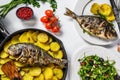 Dinner with grilled sea bream fish, arugula salad with tomatoes, baked potatoes. White background. top view Royalty Free Stock Photo