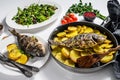 Dinner with grilled sea bream fish, arugula salad with tomatoes, baked potatoes. White background. top view Royalty Free Stock Photo