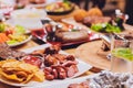 Dinner party food concept. Dinner table with grilled sausage, tortilla wraps, beer drink and different dishes on wooden Royalty Free Stock Photo