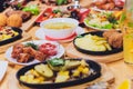 Dinner party food concept. Dinner table with grilled sausage, tortilla wraps, beer drink and different dishes on wooden Royalty Free Stock Photo