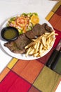 Dinner plate with beef salad and French fries. Traditional lunch in Latin America of meat with potatoes and chimichurri Royalty Free Stock Photo