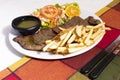 Dinner plate with beef salad and French fries. Traditional lunch in Latin America of meat with potatoes and chimichurri Royalty Free Stock Photo