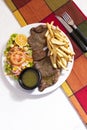 Dinner plate with beef salad and French fries. Traditional lunch in Latin America of meat with potatoes and chimichurri Royalty Free Stock Photo