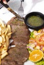 Dinner plate with beef salad and French fries. Traditional lunch in Latin America of meat with potatoes and chimichurri Royalty Free Stock Photo