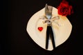 Dinner set with heart, red rose, black background. Royalty Free Stock Photo