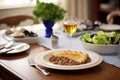 a dinner setting with moussaka taking the center place on a table