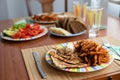 Dinner table with salad dish, chicken, sweet potatoes, bread and colorful water glass