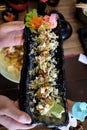 In selective focus a row of avocado roll sushi in a black tray with a female hands holding Royalty Free Stock Photo