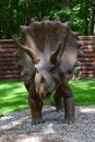 Dino Park Triceratops huge dinosaur of Jurassic era walks in the forest in summer on a sunny day Royalty Free Stock Photo
