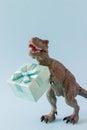 Dinosaur holds a gift box. Minimal concept. Idea