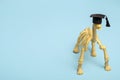 Dinosaur skeleton in a student hat on a blue background. Medical education concept, study of osteology with copy space