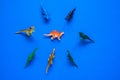 dinosaurs on blue background, a crowd of toy dinosaurs surrounded one dinosaur