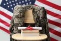 Diploma, books and soldier uniform on wooden chair near flag of United States. Military education