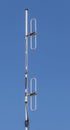 Dipole antenna for telecommunications with blue sky background.