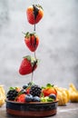 Dipping dark chocolate on flying strawberry into porceline pot with chocolate on white marble background Royalty Free Stock Photo