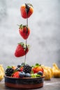 Dipping dark chocolate on flying strawberry into porceline pot with chocolate on white marble Royalty Free Stock Photo