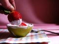 Dipping fresh strawberries in Greek yogurt close up shot