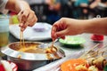 Dipping ingredients and seafood sticks in warming satay sauce.