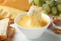 Dipping piece of bread into bowl with delicious cheese fondue Royalty Free Stock Photo