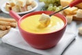 Dipping piece of bread into tasty cheese fondue at grey table Royalty Free Stock Photo