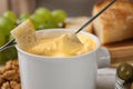 Dipping pieces of bread into tasty cheese fondue on table Royalty Free Stock Photo