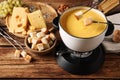 Dipping pieces of bread into tasty cheese fondue at wooden table Royalty Free Stock Photo