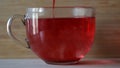 Dipping red tea bag in a transparent mug with hot water on wooden wall background. Concept. Close up of brewing of red Royalty Free Stock Photo