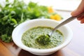 dipping a spoon in salsa verde, cilantro on top