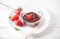 Dipping strawberry in chocolate cream on white wood