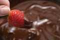 Dipping strawberry into dark premium chocolate Royalty Free Stock Photo