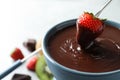 Dipping strawberry into fondue pot with chocolate