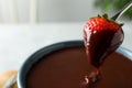 Dipping strawberry into fondue pot with chocolate, closeup. Space for text