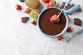 Dipping strawberry into fondue pot with chocolate on light grey marble table, top view. Space for text Royalty Free Stock Photo