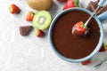 Dipping strawberry into fondue pot with chocolate on light grey marble table, top view. Space for text Royalty Free Stock Photo