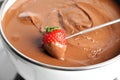 Dipping strawberry into pot with tasty chocolate fondue Royalty Free Stock Photo