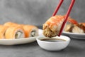 Dipping tasty nigiri sushi with shrimp into soy sauce on grey table, closeup Royalty Free Stock Photo