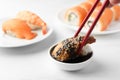 Dipping tasty nigiri sushi with smoked eel into soy sauce on white table, closeup