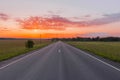 Direct asphalt road in the middle of a wheat field illuminated by a beautiful sunrise