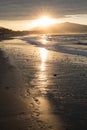 Direct golden sunset`s sunlight on a scenic sandy beach in hendaye in dramatic cloudy atmosphere, basque country, france Royalty Free Stock Photo