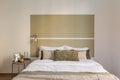 Direct horizontal shot of a double bed in a honeymoon hotel room in beige and olive tones. The concept of a stylish