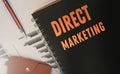 Direct marketing words written on copybook cover on financial reports, pen and leather wallet. Selective focus. Business Concept
