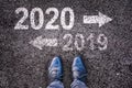 2020 and 2019 with direction arrows written on asphalt road background with legs Royalty Free Stock Photo